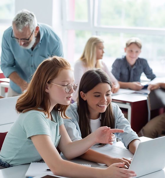 Middle school students collaborating on a laptop in class